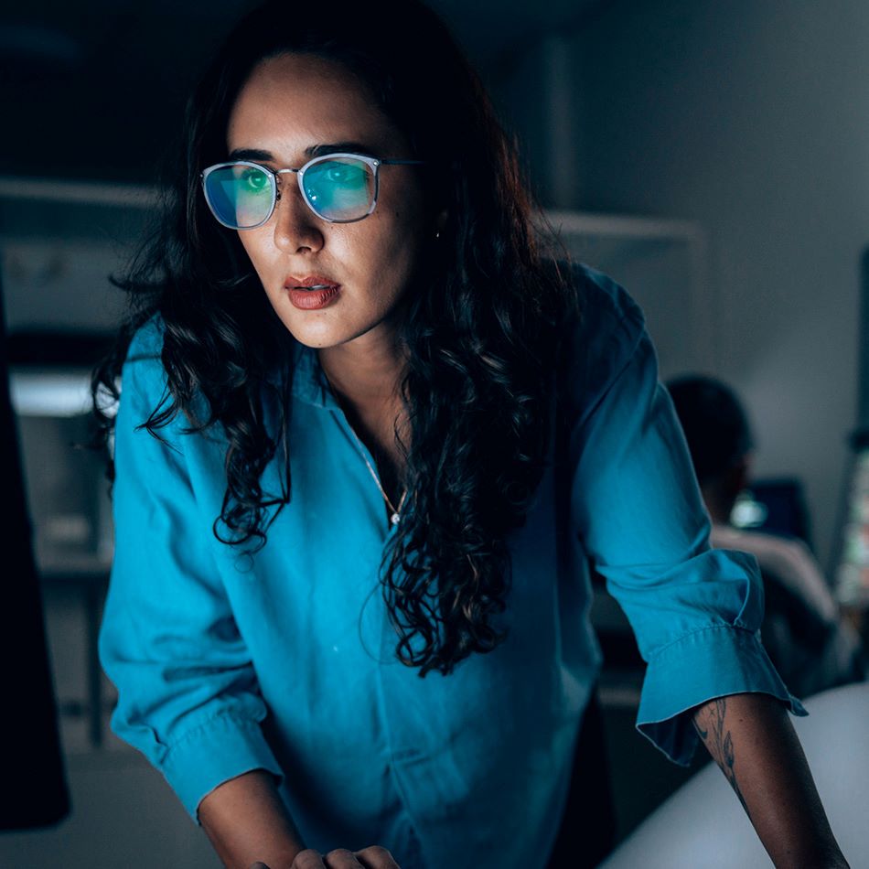 cybersecurity professional looking at computer monitor in dimly lit room