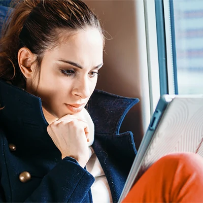 Woman sitting on a train looking at her tablet
