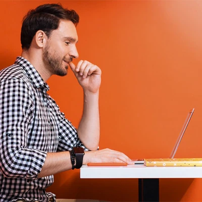 Man sitting at table looking at laptop