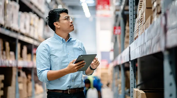A man looking at a shelf and taking notes